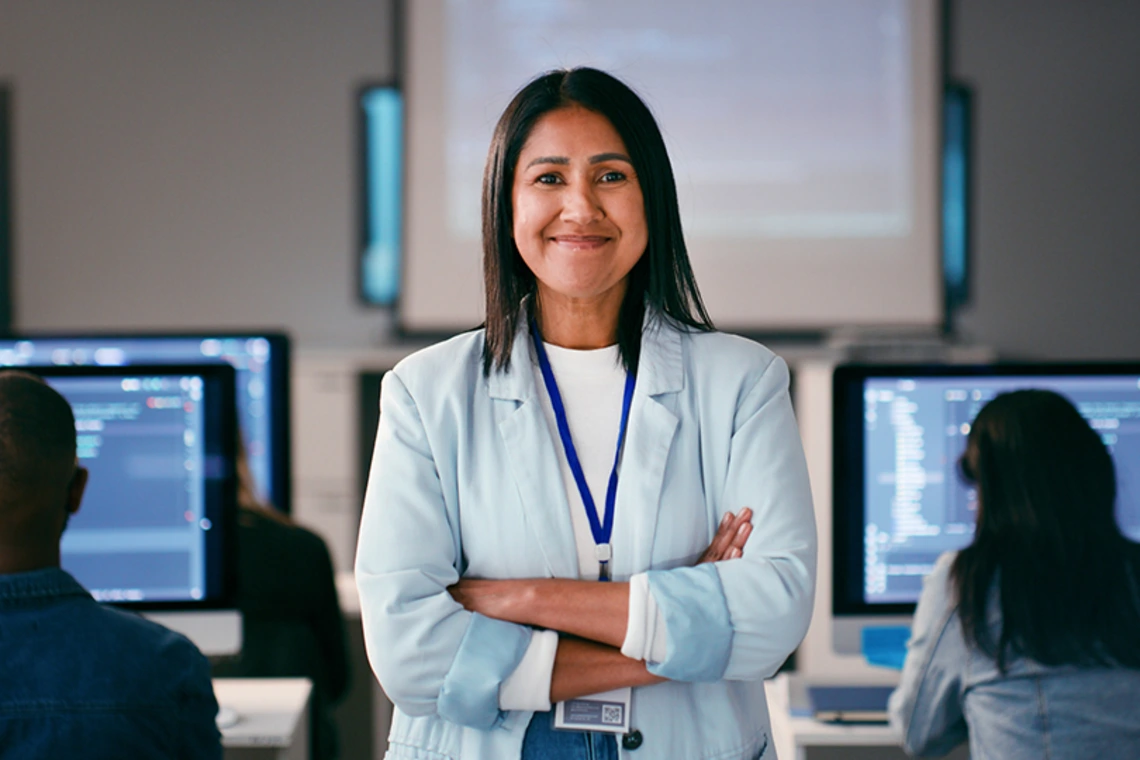 Smiling staff member with arms crossed in classroom