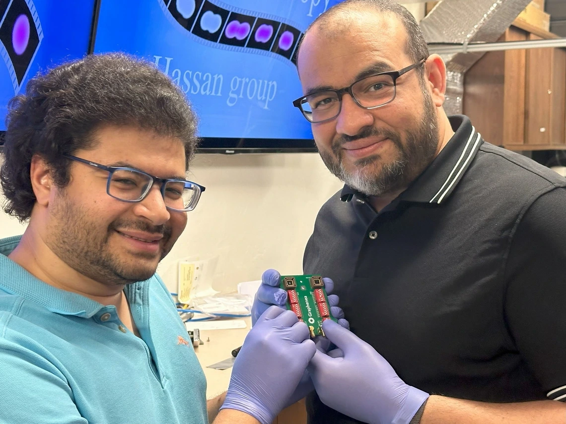 Mohammed Hassan (right), associate professor of physics and optical sciences, and Mohamed Sennary, a graduate student studying optics and physics, holding the commercial transistor they used to develop a petahertz-speed transistor.