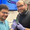 Mohammed Hassan (right), associate professor of physics and optical sciences, and Mohamed Sennary, a graduate student studying optics and physics, holding the commercial transistor they used to develop a petahertz-speed transistor.
